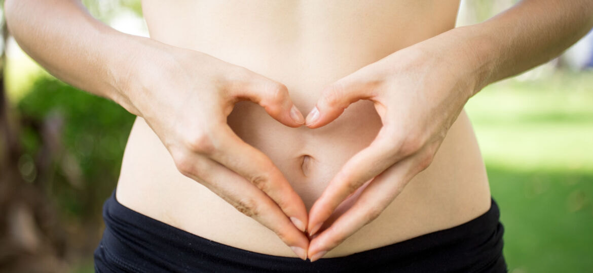 Close-up of female hands shaping heart on belly